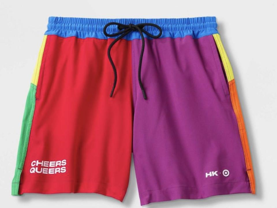 A color blocked pair of swim trunks with "cheers queers" on the left bottom leg.