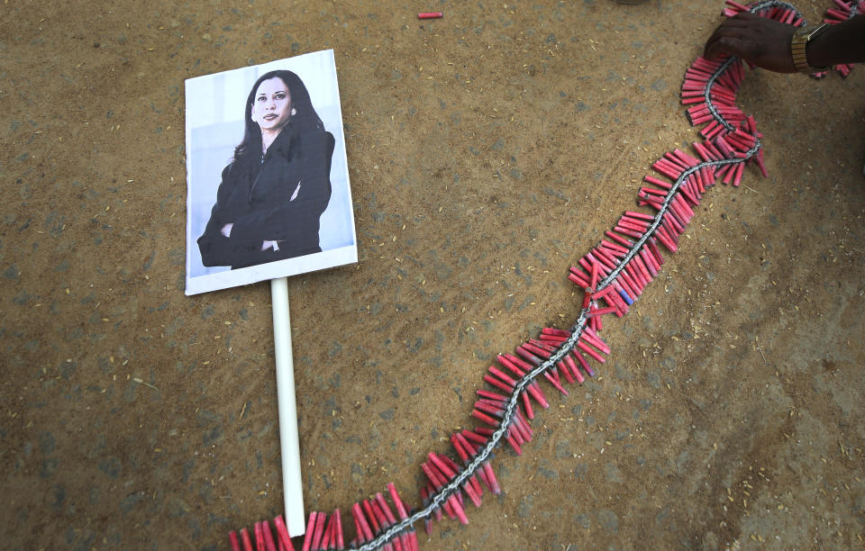 A portrait of U.S. Vice President-elect Kamala Harris lies on the ground as a villager prepares to burst firecrackers ahead of Harris' inauguration, in Thulasendrapuram, the hometown of Harris' maternal grandfather, south of Chennai, Tamil Nadu state, India, Wednesday, Jan. 20, 2021. A tiny, lush-green Indian village surrounded by rice paddy fields was beaming with joy Wednesday hours before its descendant, Kamala Harris, takes her oath of office and becomes the U.S. vice president. (AP Photo/Aijaz Rahi)