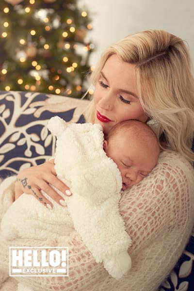 Joss Stone cuddles her newborn with the Christmas tree in the background