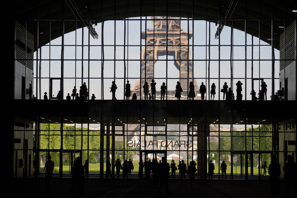 FILE - In htis Wednesday, June 9, 2021 file photo, visitors gather during a presentation visit of the "Grand Palais Ephemere", with the Eiffel Tower in the background, in Paris. Europe is opening up to Americans and other visitors after more than a year of COVID-induced restrictions. European governments hope to lure back tourists - and their dollars - back to the continent’s trattorias, vistas and cultural treasures. (AP Photo/Francois Mori, File)