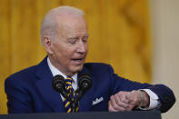 President Joe Biden looks at his watch as he talks about staying to keep answering questions from reporters during a news conference in the East Room of the White House in Washington, Wednesday, Jan. 19, 2022. (AP Photo/Susan Walsh)