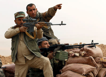 A Kurdish Peshmerga fighter aims to fire during a battle with Islamic State militants at Topzawa village, near Bashiqa, near Mosul, Iraq. REUTERS/Ahmed Jadallah