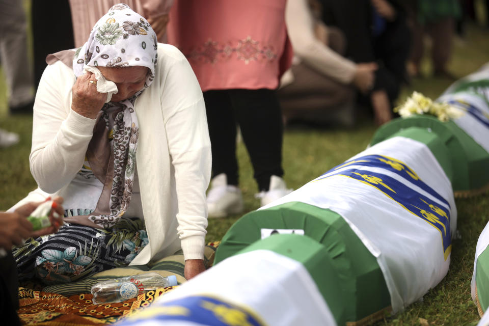 A Bosnian muslim woman mourns next to the coffin containing remains of a family member who is amongst the 50 newly identified victims of the Srebrenica Genocide, in Potocari, Monday, July 11, 2022. Fifty newly identified victims were honored and reburied Monday in Bosnia as thousands gathered to commemorate the anniversary of the 1995 Srebrenica massacre, Europe’s only acknowledged genocide since the Holocaust.(AP Photo/Armin Durgut)