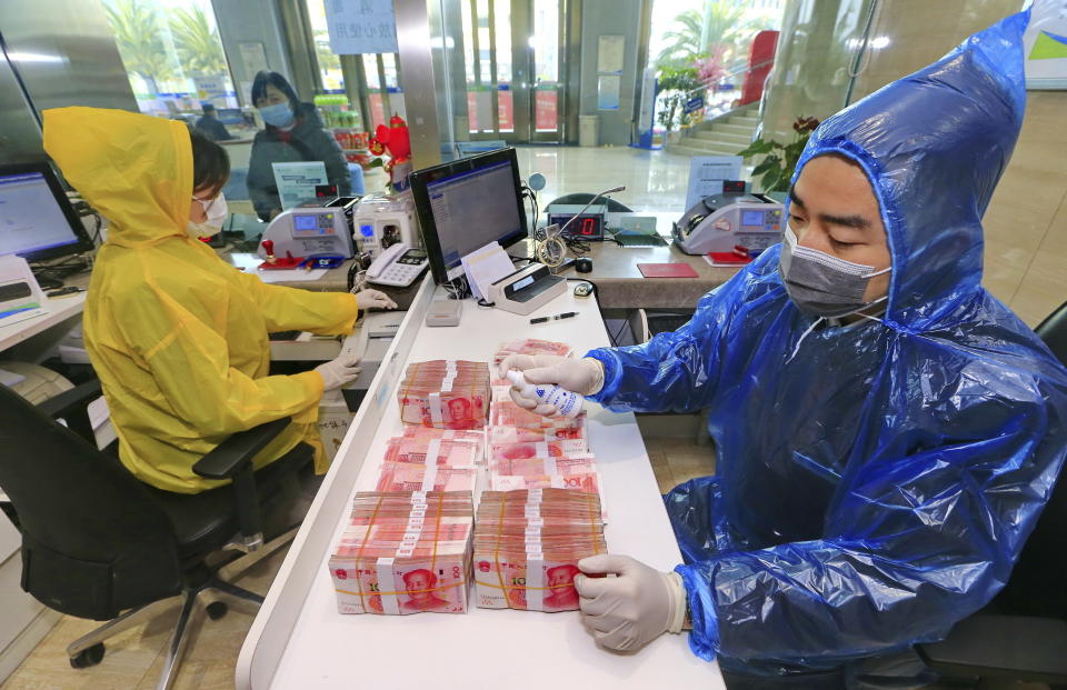 Un trabajador bancario desinfecta billetes en las instalaciones del Banco Suining en la ciudad de Suining en la provincia de Sichuan, en el suroeste de China, el miércoles 26 de febrero de 2020. (Chinatopix vía AP)