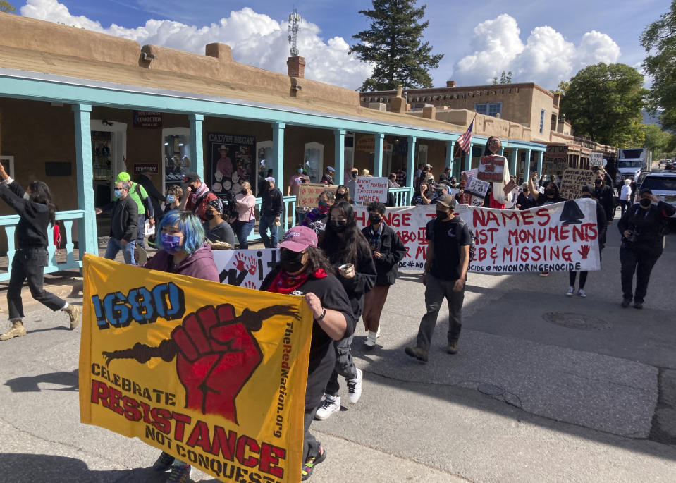 About two dozen advocates for Native American communities gather in downtown Santa Fe, N.M., Monday, Oct. 10, 2022, when most government offices were closed in commemoration of Indigenous Peoples' Day, a state holiday. Protesters left paint splashed across a monument to 19th century trapper-turned-soldier Kit Carson, outside a federal courthouse. Carson is revered and reviled as a pivotal figure in the settlement of the American West and deadly military campaigns against Native Americans including the Navajo. Demonstrators chanted, "This is Native land," and "1680," in reference to the year of the Pueblo Indian Revolt that drove Spanish settlers out of the region for a dozen years. Signs and banners also called for justice concerning missing and murdered Indigenous women. (AP Photo/Morgan Lee)