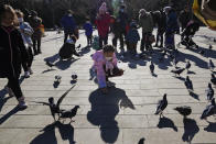 A child feeds pigeons at a park in Beijing, China, Thursday, Jan. 13, 2022. The number of babies born in China continued to shrink last year in a decade-long trend, official data showed Monday, Jan. 17, as a declining workforce adds pressure to the ruling Communist Party's ambitions to boost national wealth and global influence. (AP Photo/Ng Han Guan)