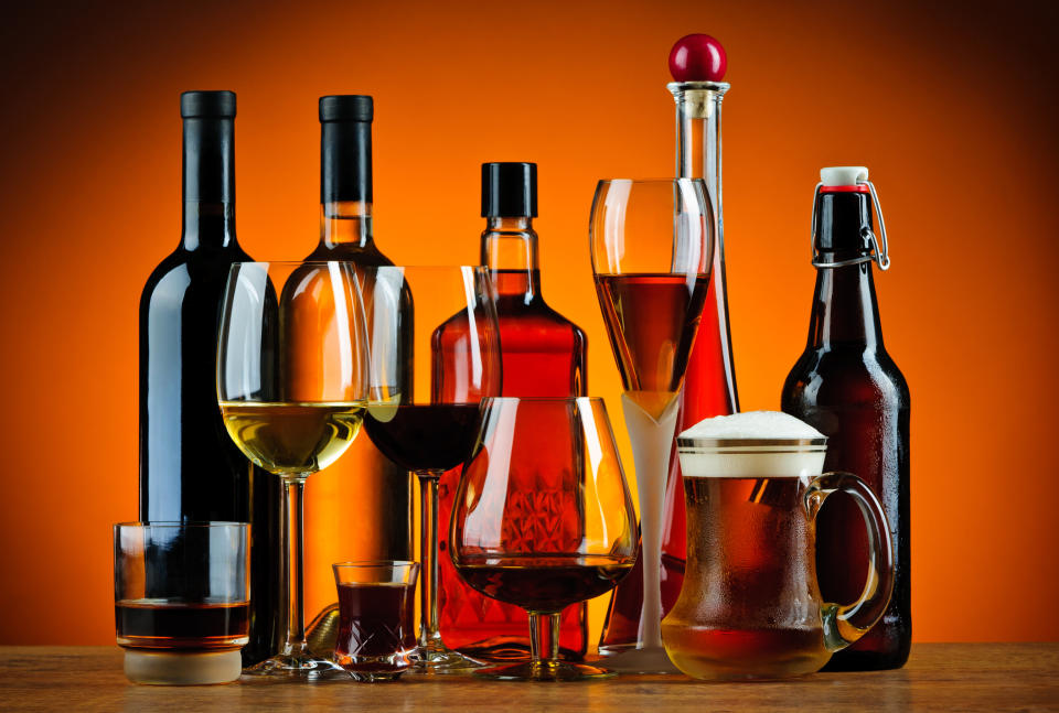 Various glasses of alcohol sitting on a bar top.