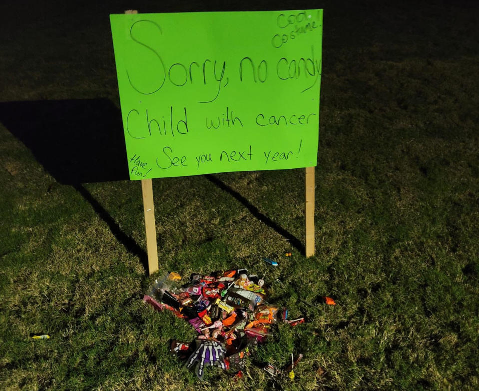 A sign outside a home tells people 'no candy' because a child with cancer is inside. Lollies sit at the base of the sign.