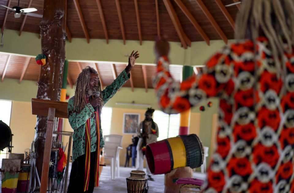 Ras Ibatash, a priest with the Ras Freeman Foundation for the Unification of Rastafari, left, preaches to his Rastafari congregation inside their tabernacle on Sunday, May 14, 2023, in Liberta, Antigua. (AP Photo/Jessie Wardarski)