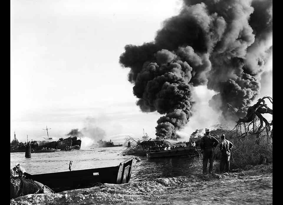 Smoke rises from the wreck of USS LST-480, at right, as tugs and other craft try to put out her fires in Pearl Harbor, Hawaii's West Loch area. 