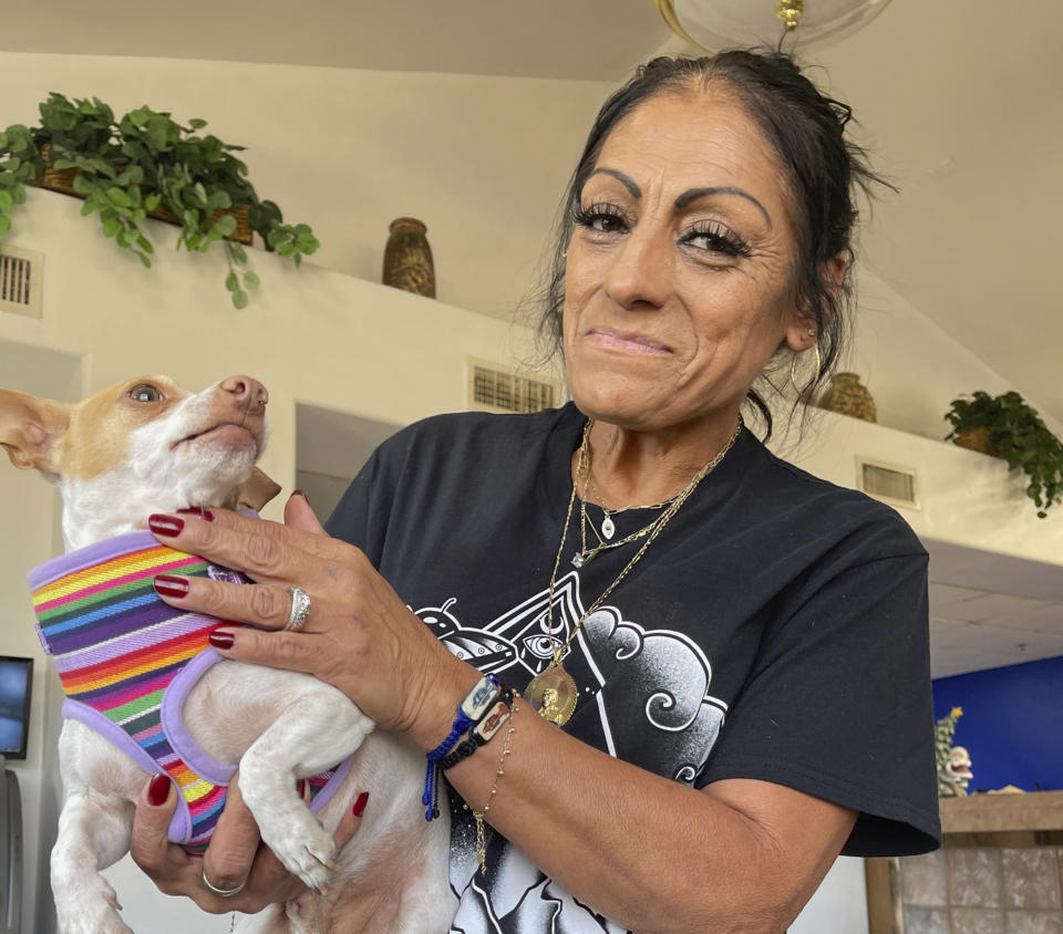 Angelita Saldaña shows off her pet Chihuahua Gaspar at a homeless shelter for older people in Phoenix, Arizona, Wednesday, Nov. 28, 2023. Saldaña says she ended up homeless when her marriage ended and for months slept in her truck in parking lots around the Phoenix area. She said her $941 monthly disability check isn't enough to pay for even a studio apartment in the area, where rents start at around $1,200. (AP Photo/Anita Snow)