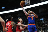 New York Knicks guard Josh Hart (3) scores as Toronto Raptors forward Jalen McDaniels (2) and forward Kelly Olynyk, center, defend during the second half of an NBA basketball game Wednesday, March 27, 2024, in Toronto. (Frank Gunn/The Canadian Press via AP)