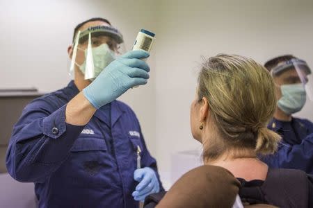 A U.S. Coast Guard Corpsman working with the Office of Field Operations checks the temperature of a traveler who has recently traveled to either Guinea, Sierra Leone, or Liberia in this handout picture from the U.S. Customs and Border Protection taken at Washington Dulles International Airport October 16, 2014. REUTERS/U.S. Customs and Border Protection/Josh Denmark/Handout via Reuters