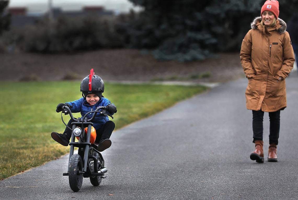 Three-year-old Cristiano Perez adds pizzazz to his riding style while zooming along the pathway on his battery-powered toy motorcycle in Claybell Park during a morning trek with his mother, Vanessa Perez, in south Richland. Bob Brawdy/bbrawdy@tricityherald.com