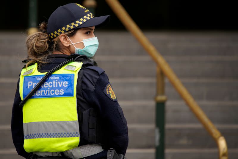 FILE PHOTO: A Protective Services Officer wearing a face mask patrols Flinders Street station in Melbourne, the first city in Australia to enforce mask-wearing to curb a resurgence of COVID-19