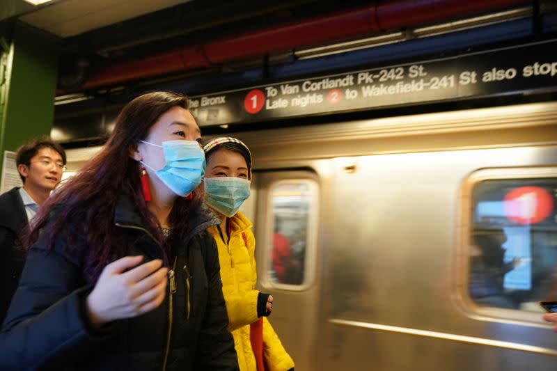 People wear surgical masks in the subway station at Times Square in New York