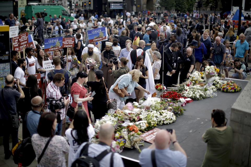 People look at flowers laid after a minute's silence on London Bridge to mark the one year anniversary of the attack that happened there, in London, Sunday, June 3, 2018. Britain's resolve to "stand firm" against terrorism is stronger than ever, Prime Minister Theresa May said Sunday, a year since a deadly vehicle-and-knife attack on London Bridge. Eight people were killed and almost 50 injured when three Islamic State group-inspired attackers ran down pedestrians on the bridge, then stabbed people at bars and restaurants in nearby Borough Market. (AP Photo/Matt Dunham)