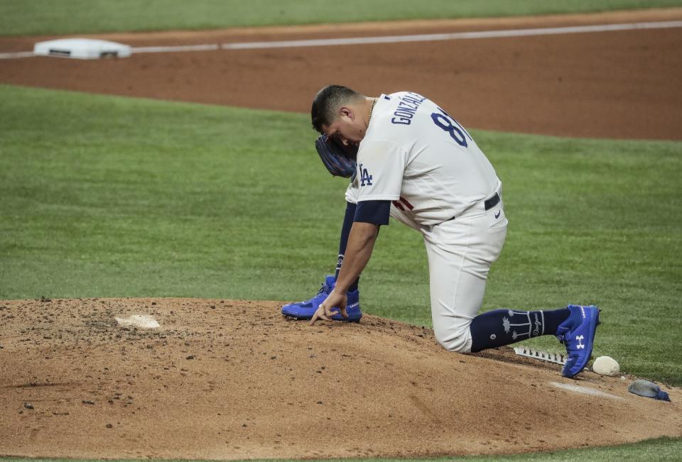 Dodgers reliever Victor González writes in the dirt on the pitching mound.