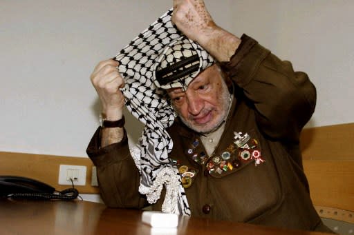 L'ex-leader palestinien Yasser Arafat ajuste son keffieh, lors d'un meeting à Ramallah en 2004 (Photo by JAMAL ARURI / AFP)