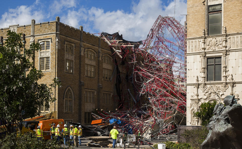 Construction workers begin cleaning up collapsed scaffolding on the 300 block of East Martin Street Friday, Sept. 20, 2019 in San Antonio. Officials say three bystanders were slightly hurt as a 100-foot (30-meter) section of scaffolding collapsed on a San Antonio street amid 50 mph (80 kph) winds from a system linked to Tropical Storm Imelda. The scaffolding, along a high-rise building, crushed several parked vehicles and crashed into St. Mark's Episcopal Church. (Daniel Carde/The San Antonio Express-News via AP)