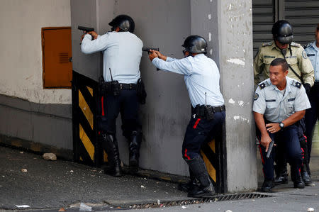 Police officers exchange fire with people shooting from inside a building housing the transport ministry in Caracas, Venezuela April 30, 2019. REUTERS/Carlos Garcia Rawlins