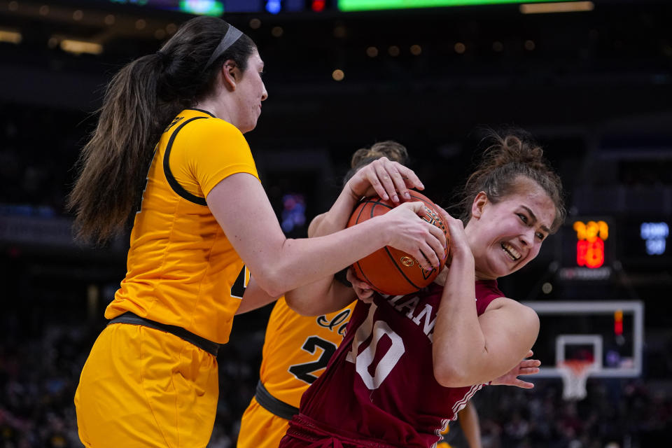 Iowa guard McKenna Warnock (14) forces a jump ball with Indiana forward Aleksa Gulbe (10) in the second half of an NCAA college basketball game for the championship of the Big Ten Conference tournament in Indianapolis, Sunday, March 6, 2022. Iowa defeated Indiana 74-67. (AP Photo/Michael Conroy)