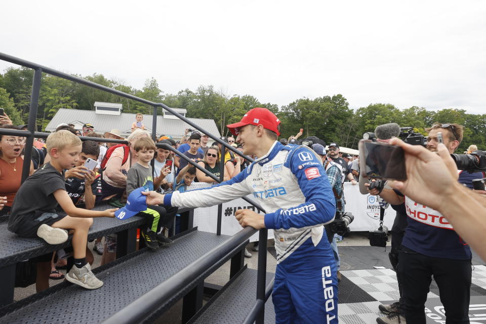 Alex Palou, center, celebrates by giving a child a signed cap after winning an IndyCar race at Road America in Elkhart Lake, Wisc., Sunday, June 20, 2021. (AP Photo/Jeffrey Phelps)