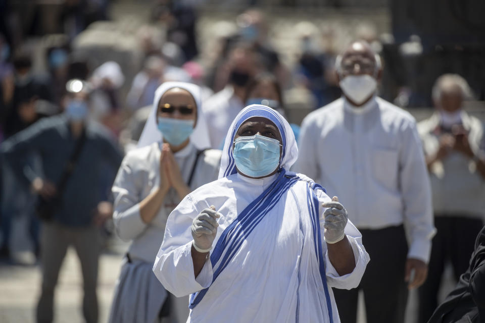 A nuns wearing gloves and mask to prevent the spread of COVID-19 stands in St. Peter's Square at the Vatican, Sunday, May 31, 2020. Pope Francis has cheerfully greeted people in St. Peter’s Square on Sunday, as he resumed his practice of speaking to the faithful there for the first time since lockdown began in Italy and at the Vatican in early March. Instead of the tens of thousands of people who might have turned out on a similarly brilliantly sunny day like this Sunday, in pre-pandemic times, perhaps a few hundred came to the square, standing well apart from others or in small family groups. (AP Photo/Alessandra Tarantino)