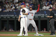 Washington Nationals' Luis Garcia Jr. (2) celebrates his RBI single behind Texas Rangers first baseman Nathaniel Lowe and umpire Edwin Jimenez, right, in the first inning of a baseball game in Arlington, Texas, Tuesday, April 30, 2024. CJ Abrams scored on the hit. (AP Photo/Tony Gutierrez)