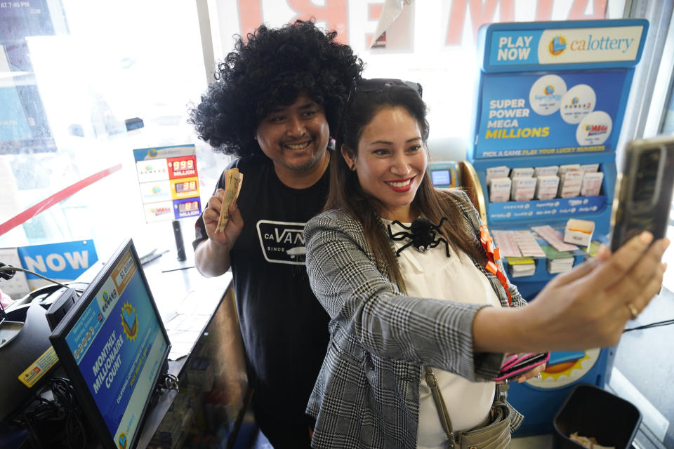 Cathy Zubiate, from Long Beach, Calif., and Gilbert Estrella, from Whitter, Calif., take a selfie after purchasing about $400.00 worth of lottery tickets for the Powerball lottery at the Blue Bird Liquor store in Hawthorne, Calif., Monday, Oct. 31, 2022. The jackpot for Monday night's drawing soared after no one matched all six numbers in Saturday night's drawing. It's the fifth-largest lottery jackpot in U.S. history. (AP Photo/Damian Dovarganes)