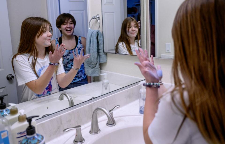 Two siblings laugh while washing chalk off their hands.