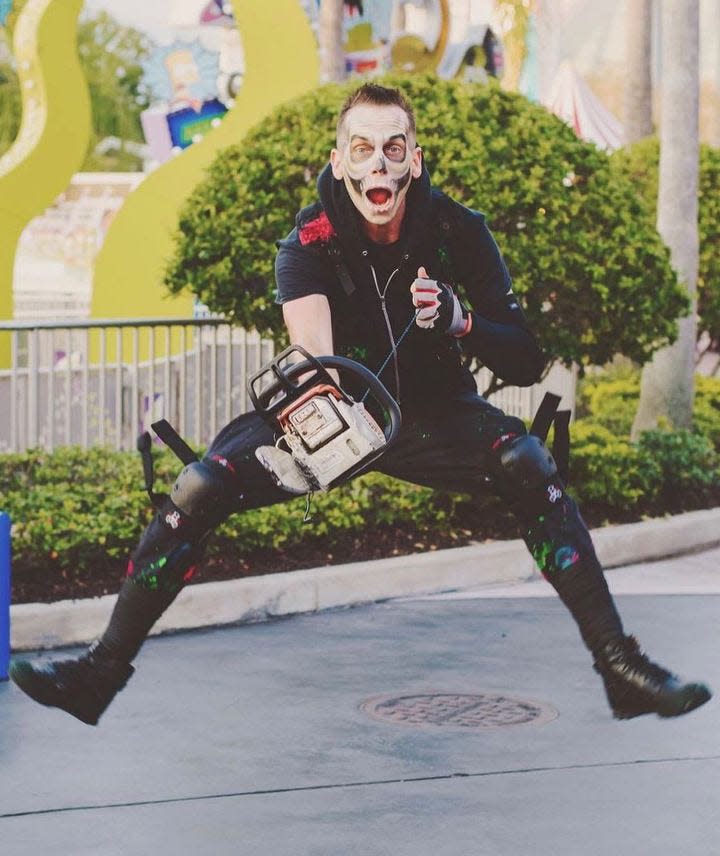 Halloween Horror Nights employee holding a fake chainsaw.