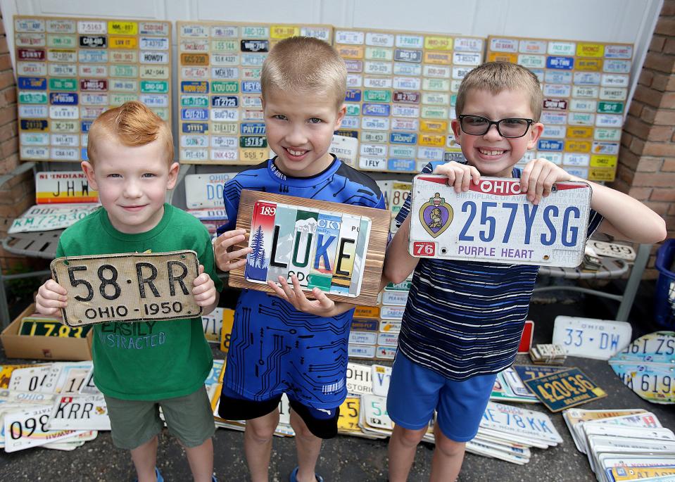 Seven-year-old Luke Reicosky, center, is pictured with his brothers Finn, left, 5, and twin brother Beau. They are showing off some of the license plates in Luke's extensive collection.