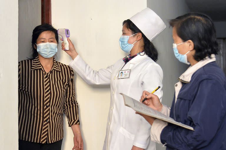 En esta imagen de archivo, distribuida por el gobierno de Corea del Norte, una doctora toma la temperatura a un residente para tratar de frenar la propagación del coronavirus, en Pyongyang, Corea del Norte, el 17 de mayo de 2022. (Agencia Central de Noticias de Corea/Korea News Service vía AP, archivo)