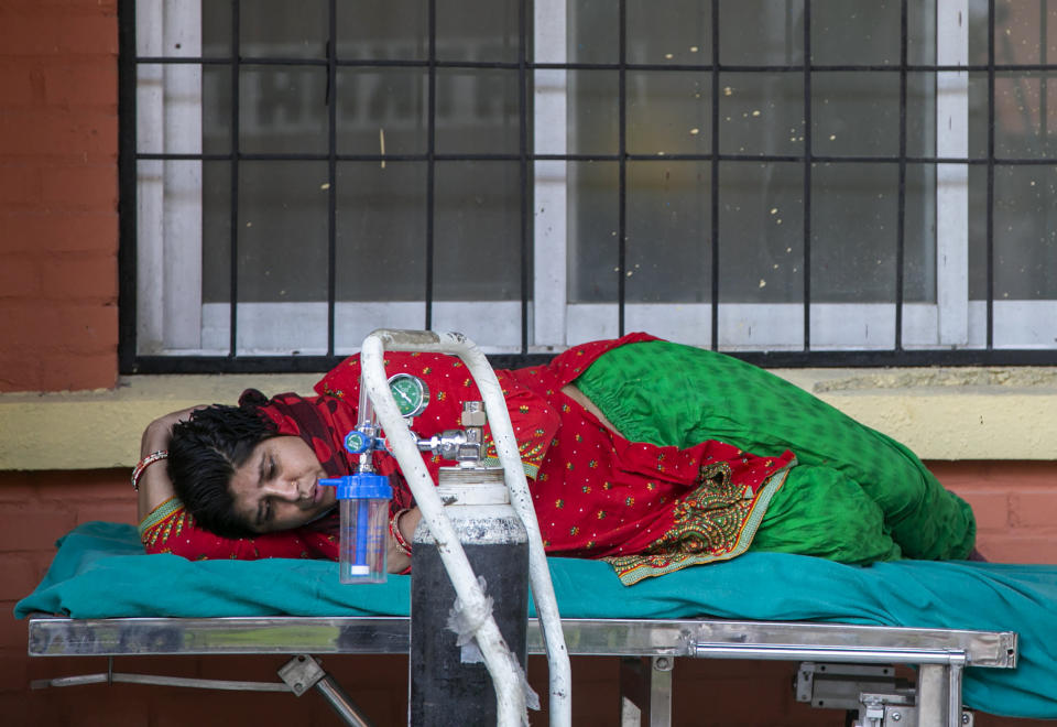 A COVID-19 patient waits to receive oxygen outside an emergency ward of a hospital in Kathmandu, Nepal, Thursday, May 6, 2021. Nepal's main cities and towns including the capital Kathmandu has been in lockdown since last month as the number coronavirus cases and deaths continue to rise. (AP Photo/Niranjan Shrestha)