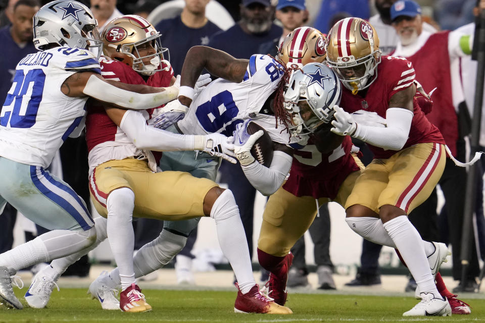 Dallas Cowboys wide receiver CeeDee Lamb, middle, is tackled by San Francisco 49ers defenders during the first half of an NFL football game in Santa Clara, Calif., Sunday, Oct. 8, 2023. (AP Photo/Godofredo A. Vásquez)