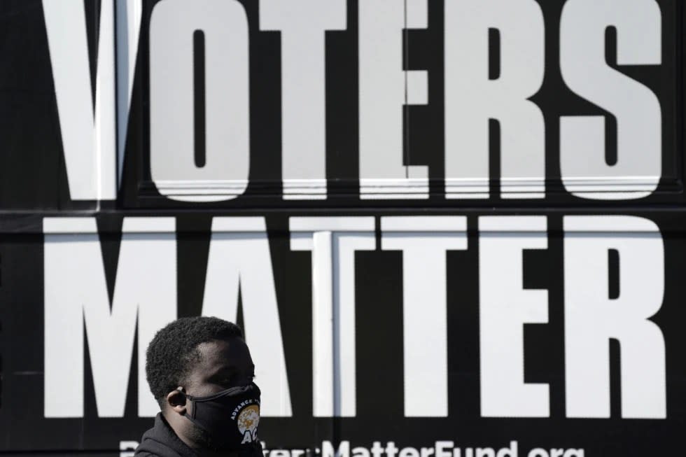 A man wearing a mask gathers with a group in support of Black Voters Matter at the Graham Civic Center polling site in Graham, N.C., Nov. 3, 2020. (AP Photo/Gerry Broome, File)