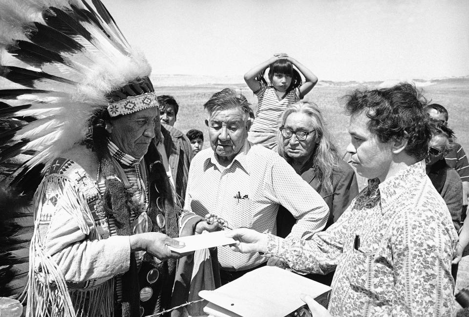 FILE - In this May 5, 1973 file photo Hank Adams, right, permanent representative of the Indians Trial of Broken Treaties presents letter from the White House to traditional Sioux Chief Frank Fools Crow, left, at border of Pine Ridge Reservation in Scenic,. S.D. Henry “Hank” Adams, Assiniboine-Sioux, died Dec. 21, 2020 at St. Peter’s Hospital in Olympia, Wash., according to the Northwest Indian Fisheries Commission. Influential Native American rights advocate and author Vine Deloria Jr. called Adams the "most important Indian" because he was involved with nearly every major event in American Indian history from the 1960s forward. (AP Photo, File)