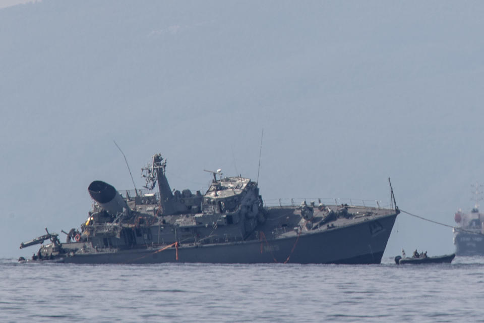 Α damaged navy minesweeper is being towed near the port of Piraeus on Tuesday, Oct. 27, 2020. Greece's coast guard says a Greek navy minesweeper and a Portuguese-flagged cargo ship have collided outside the country's main port of Piraeus, leaving two navy crew slightly injured and prompting the evacuation of the military vessel. (AP Photo/Petros Giannakouris)