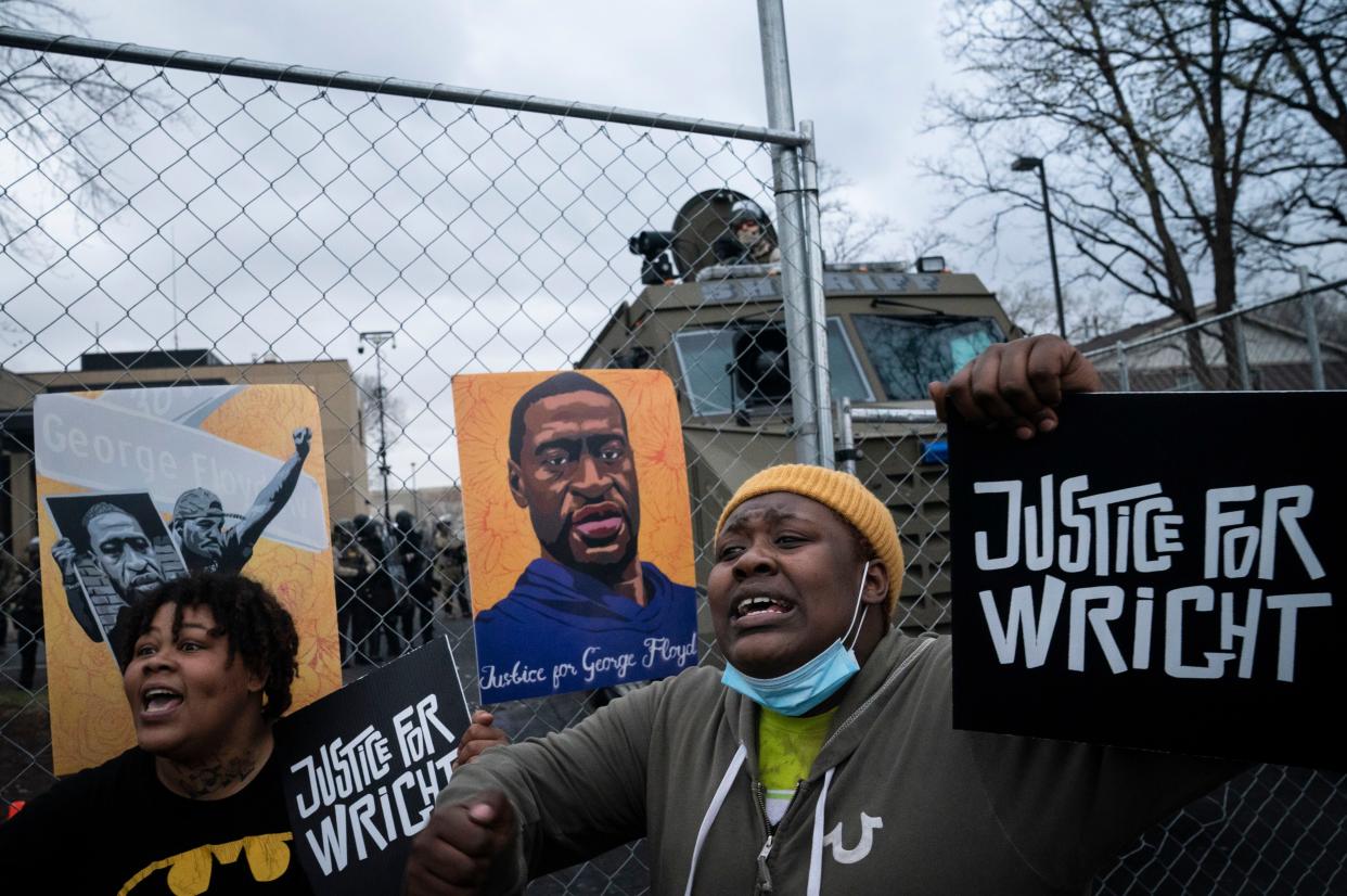 Demonstrators shout along a perimeter fence guarded by law enforcement officers during a protest over Sunday's fatal shooting of Daunte Wright outside the Brooklyn Center Police Department, Wednesday, April 14, 2021, in Brooklyn Center, Minn.