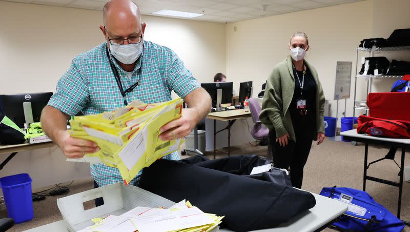 Michael Fife removes ballots from a bag as election workers process ballots at the Salt Lake County Clerk’s Office in Salt Lake City on Nov. 3, 2020.