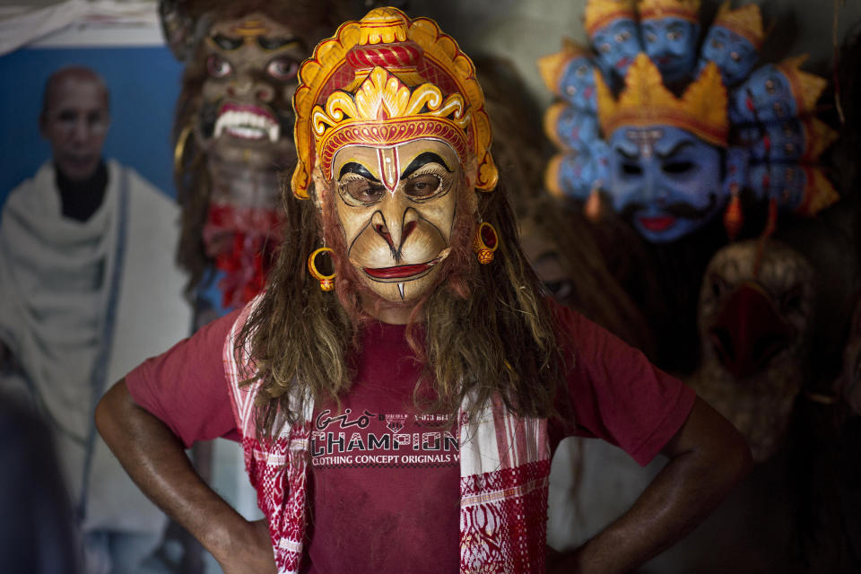 In this Tuesday, Aug. 7, 2018 photo, mask maker Khagen Goswami wears a mask of Hindu monkey god Hanuman at Samaguri Satra, a Vaishnavite monastery, in Majuli, India. Vaishnavite practice is credited with preserving the culture of mask-making, an integral part of the dance dramas or Bhaonas. At the Samaguri Satra, the monks use locally available bamboo, cane, clay, paper, jute and cow dung to shape and paint masks depicting characters from Hindu mythology. (AP Photo/Anupam Nath)
