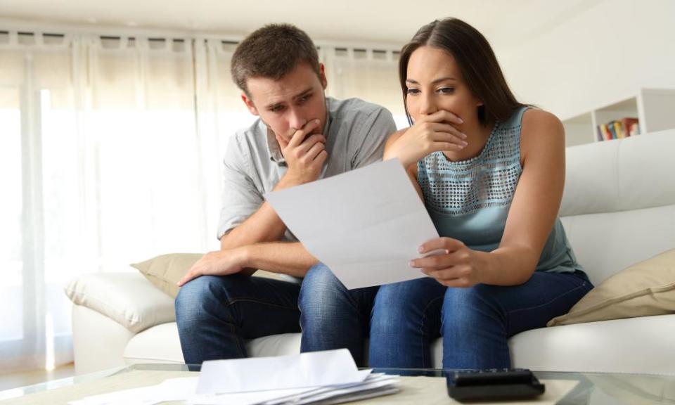 Worried couple reading a letter at home