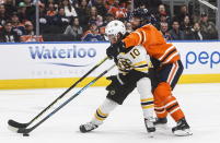 Boston Bruins left wing Anders Bjork (10) and Edmonton Oilers defenseman Adam Larsson (6) battle for the puck during the first period of an NHL hockey game, Wednesday, Feb. 19, 2020 in Edmonton, Alberta. (Jason Franson/The Canadian Press via AP)