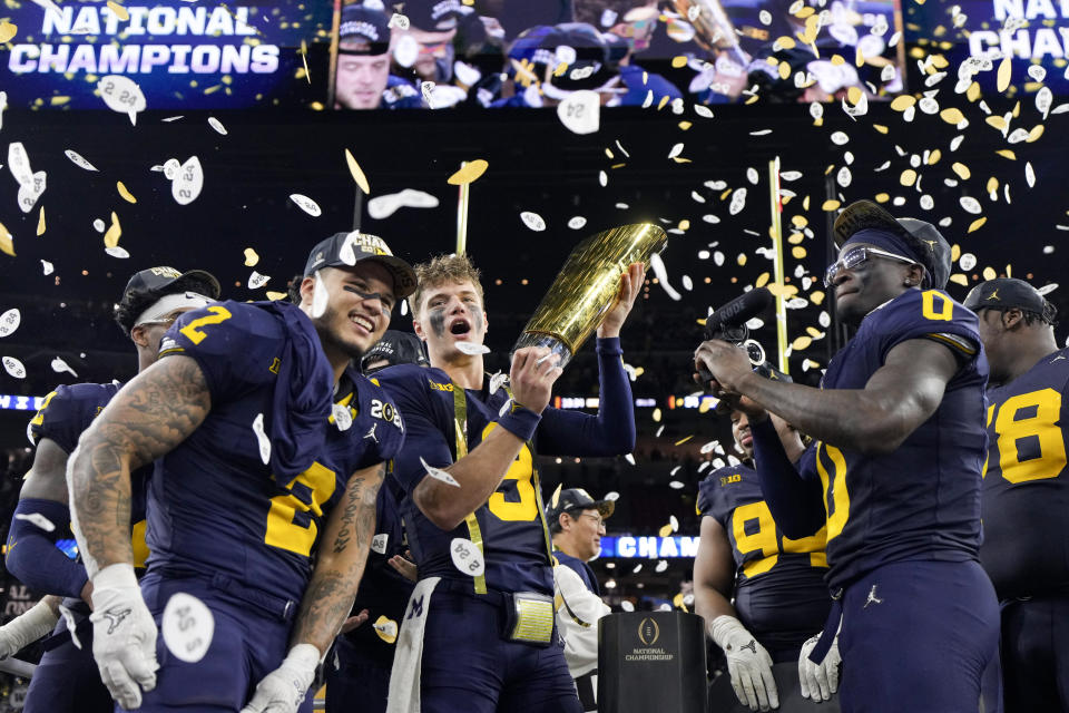 Michigan quarterback J.J. McCarthy celebrates with the trophy after their win against Washington in the national championship NCAA College Football Playoff game Monday, Jan. 8, 2024, in Houston. (AP Photo/David J. Phillip)