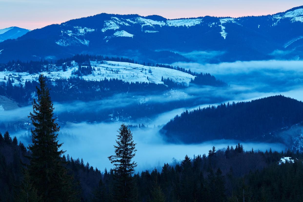 Beautiful view of the blue winter mountains and hills in Carpathians on the sunrise