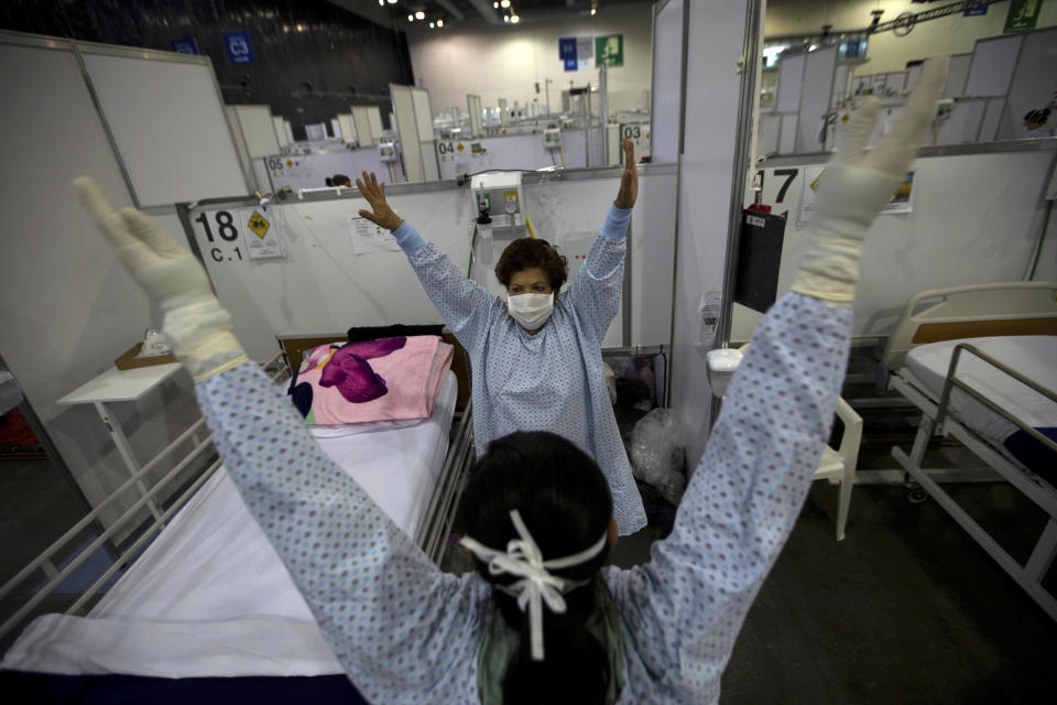 FILE - In this March 11, 2021 file photo, directed by a nurse, a COVID-19 patient, back center, stretches her arms as part of a fitness program in a field hospital built inside the Citibanamex convention center in Mexico City. Mexico’s unwillingness to spend money, do more testing, change course or react to new scientific evidence contributed to the country being one of the worst hit by the coronavirus pandemic, according to a report released the third week of April, by the University of California, San Francisco. (AP Photo/Fernando Llano, File)