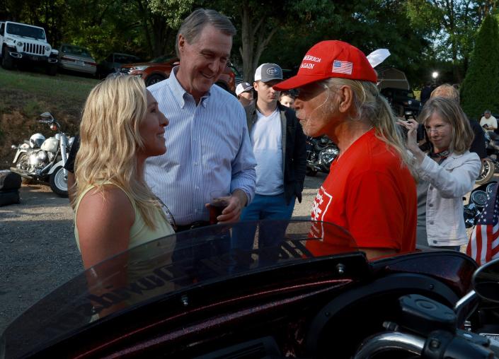 Republican Rep. Marjorie Taylor Greene of Georgia, speaks with a Trump fan as gubernatorial hopeful David Perdue (center) looks on during a Bikers for Trump campaign rally May 20 in Plainville, Georgia.