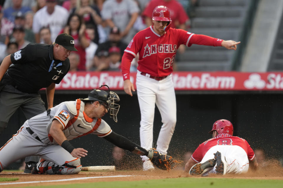 Los Angeles Angels' Mike Moustakas (8) scores off of a double hit by Hunter Renfroe ahead of a throw to San Francisco Giants catcher Blake Sabol (2) during the first inning of a baseball game in Anaheim, Calif., Tuesday, Aug. 8, 2023. Brandon Drury (23) also scored. (AP Photo/Ashley Landis)
