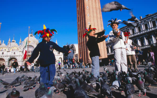 Children playing with pigeons in front of Piazza San Marco's 11th century Basilica di San Marco, Venice's cathedral since 1807.